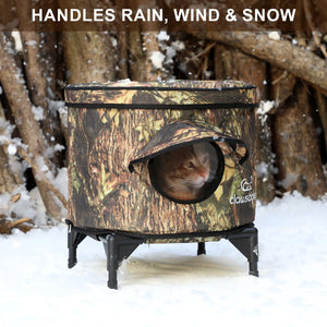 Weatherproof insulated outdoor cat house with raised base and camouflage design, keeping feral and outdoor cats warm and dry during rain, wind, and snow.